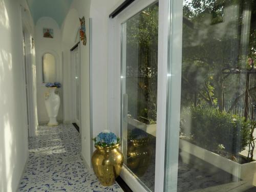 een hal met een glazen deur en een vaas op de vloer bij Maison de charme Villa Mavi in Praiano