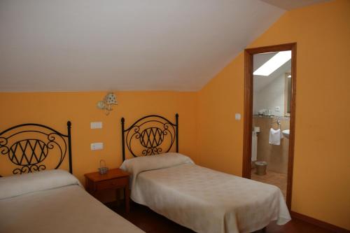 2 camas en una habitación con paredes de color naranja en El Aposento De Babia, en Quintanilla de Babia