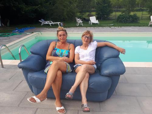 twee vrouwen op een bank naast een zwembad bij Biogarden in Zelarino