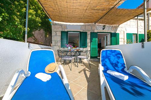 a patio with blue chairs and a table and a table and chairs at Mala Cele in Podgora
