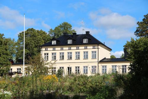 un grand bâtiment blanc avec un toit noir dans l'établissement Riddersviks Herrgård, à Stockholm