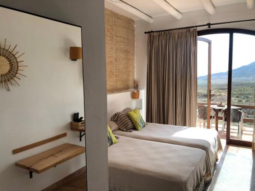 a bedroom with a bed and a large window at Cortijo El Paraíso in Los Escullos