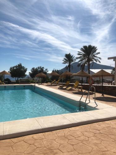einen Pool mit Stühlen und Sonnenschirmen in einem Resort in der Unterkunft Cortijo El Paraíso in Los Escullos
