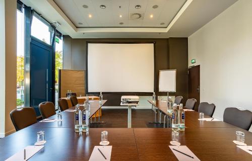 a conference room with tables and chairs and a projection screen at The Rilano Hotel München in Munich