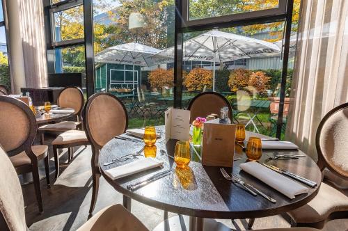 a dining room with tables and chairs and windows at The Rilano Hotel München in Munich