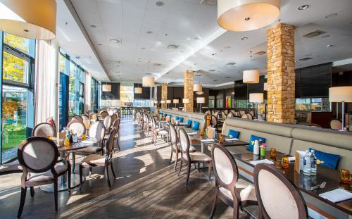 a dining room with tables and chairs and windows at The Rilano Hotel München in Munich
