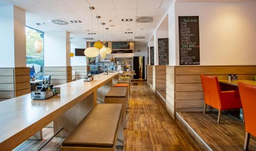 a restaurant with wooden tables and orange chairs at The Rilano Hotel München in Munich