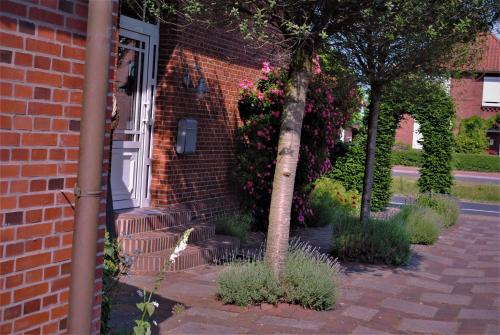 a brick house with a white door and a tree at Ferienwohnung Heckmann, 95138 in Rhauderfehn