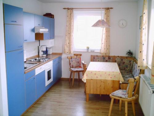 cocina con armarios azules, mesa y ventana en Komfortable Ferienwohnung am Ditzumer Sieltief, 45019, en Jemgum