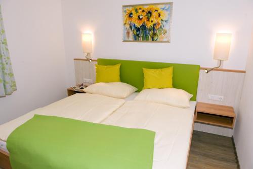 Un dormitorio con una cama verde y blanca con almohadas amarillas en Ferienwohnungen - Boarding Wohnungen Sonnenhof, en Lenzing