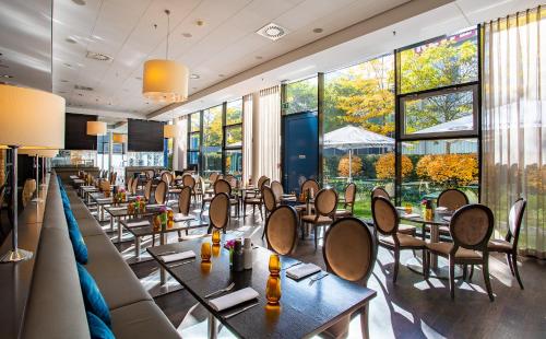 a restaurant with tables and chairs and large windows at Rilano 24/7 Hotel München in Munich