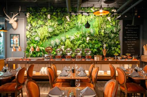 a restaurant with tables and a large wall of lettuce at Hotel Vista in Pattaya Central