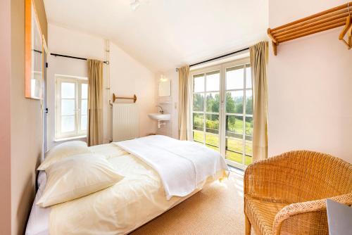 a bedroom with a bed and a large window at De Appelgaard in Sint-Martens-Voeren