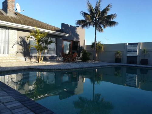 a swimming pool in front of a house with a palm tree at 420 on Cape in Port Elizabeth