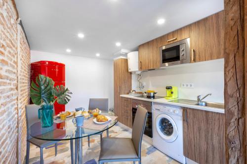 a kitchen and dining room with a table and a washing machine at Apartamentos Ejemplares in Alcalá de Henares