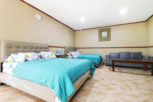 um quarto com 2 camas e um sofá em Hotel Alamanda em Jakarta