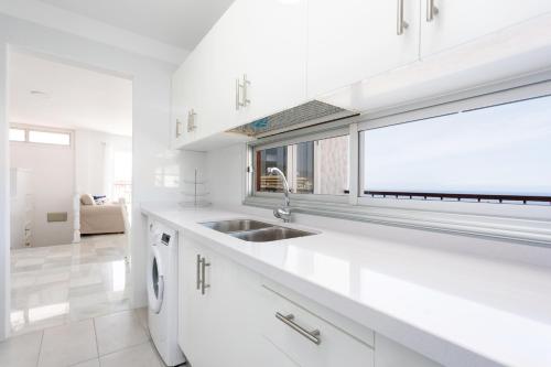 a white kitchen with a sink and a window at Home2Book Stunning Sea Views Adeje, Wifi & Pool in Playa Fañabe