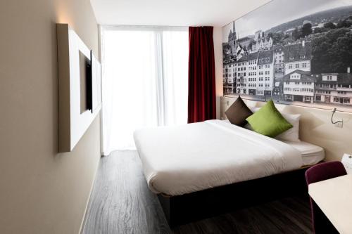 a bedroom with a white bed and a window at B&B HOTEL Zürich Wallisellen in Wallisellen