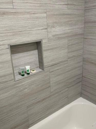 a bathroom with a tile shower with a mirror at Pacific Inn Anaheim in Anaheim
