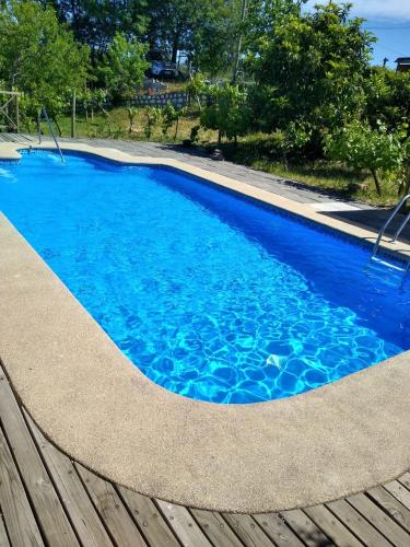 a swimming pool with blue water and a wooden deck at Cabaña Quillón El Campito in Quillón