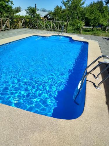 a blue swimming pool with a metal rail next to it at Cabaña Quillón El Campito in Quillón