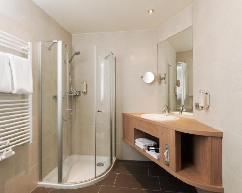 a bathroom with a glass shower and a sink at Berghotel Hohe Mark in Reken