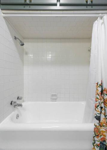 a bathroom with a white tub and a shower curtain at Classy 1927 Uptown Tudor 4 min to Magnolia in Waco