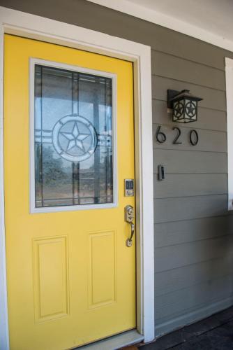 a yellow door on a house with a window at Walk to the Silos! 3 Bed 1960's Bungalow near Baylor in Waco