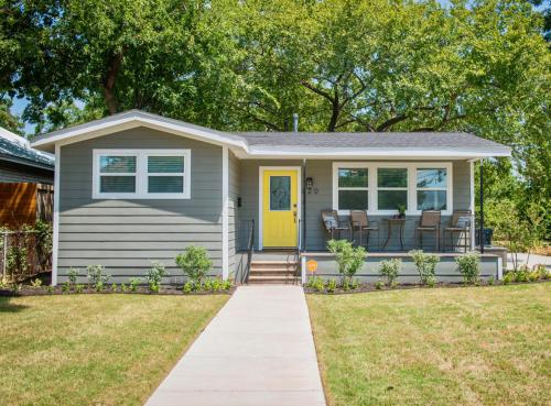 a tiny house with a yellow door on a lawn at Walk to the Silos! 3 Bed 1960's Bungalow near Baylor in Waco