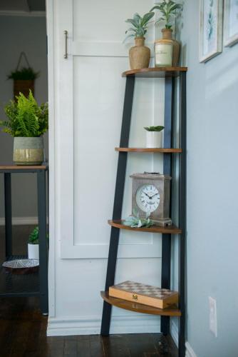 a black ladder shelf with a clock and potted plants at Walk to the Silos! 3 Bed 1960's Bungalow near Baylor in Waco