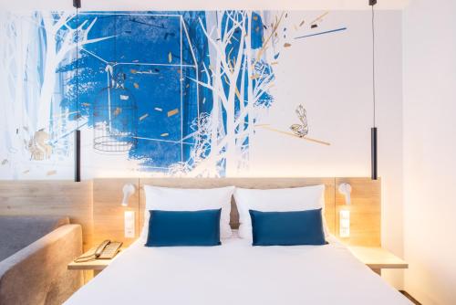 a bedroom with a large bed with blue pillows at ibis Styles Kraków East in Kraków