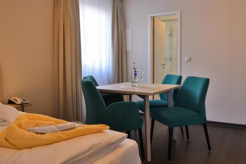 a hotel room with a table and green chairs at Sonnenhotel Bayerischer Hof - All Inklusive Angebote verfügbar in Waldmünchen