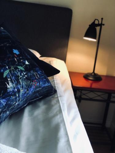 a bed with a pillow and a lamp on a table at Treetop Spa Hangout & Hotel in Gothenburg
