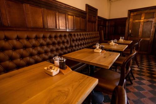 a restaurant with wooden tables and leather booths at Donington Park Farmhouse Hotel in Castle Donington
