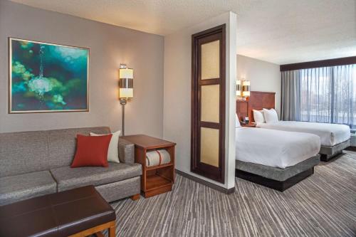 a hotel room with a bed and a couch at Hyatt Place Cincinnati Blue Ash in Blue Ash