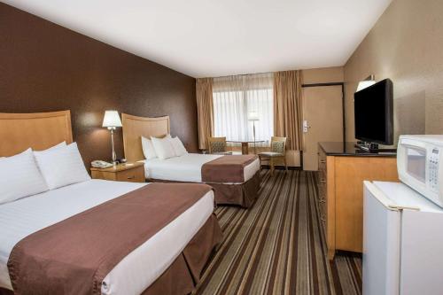 a hotel room with two beds and a flat screen tv at Travelodge by Wyndham Deltona in Deltona