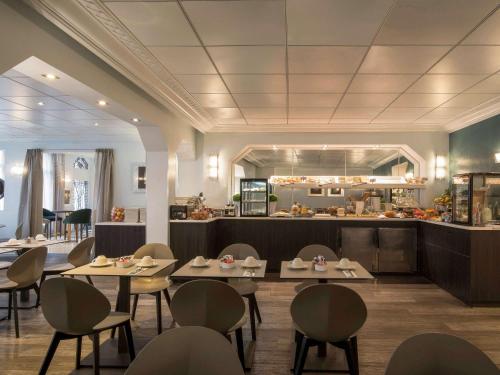 un restaurant avec des tables et des chaises et une cuisine dans l'établissement Mercure Paris Opéra Faubourg Montmartre, à Paris