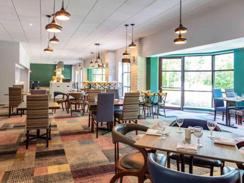a restaurant with tables and chairs and windows at Novotel Newcastle Airport in Newcastle upon Tyne