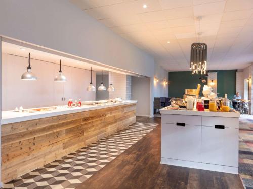 a restaurant with a counter in the middle of a room at Novotel Newcastle Airport in Newcastle upon Tyne
