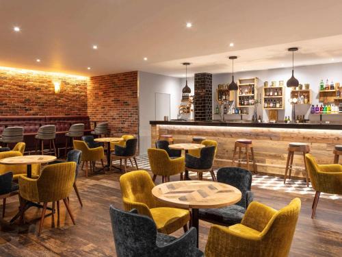 a restaurant with tables and chairs and a bar at Novotel Newcastle Airport in Newcastle upon Tyne