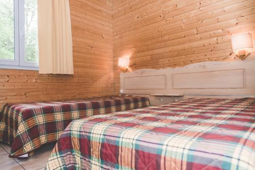 a bedroom with a bed in a wooden wall at Terres de France - Natura Resort Pescalis in Moncoutant