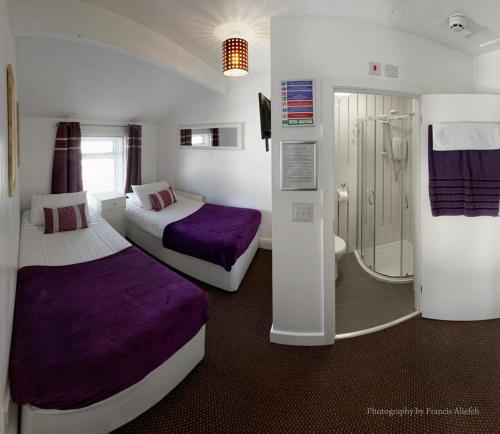 a hotel room with two beds and a shower at Ardern Hotel in Blackpool