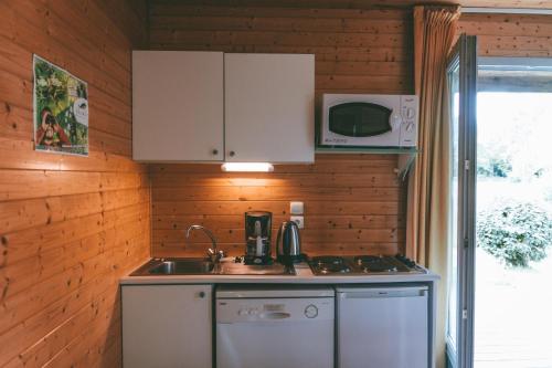 een keuken met een wastafel en een magnetron bij Terres de France - Natura Resort Pescalis in Moncoutant