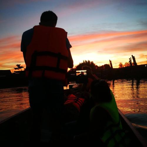a man in a boat taking a picture of the sunset at Rub Lom Chom Klong Homestay in Chumphon