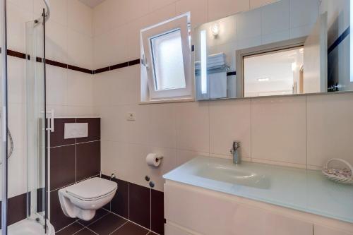 a bathroom with a toilet and a sink and a mirror at Apartments Pineta in Cunski
