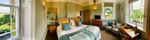 a bedroom with a bed and a couch and windows at Hassop Station rooms on the Monsal Trail in Bakewell