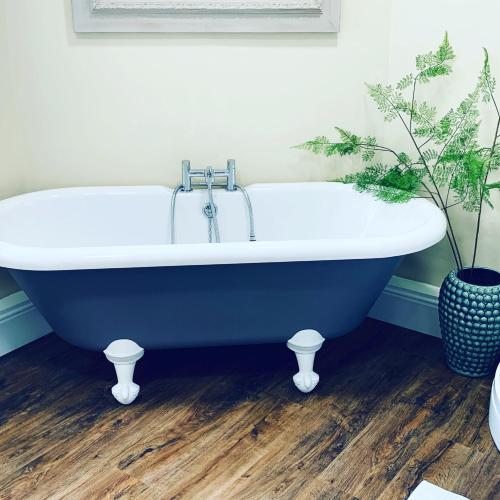 a bath tub in a bathroom with a potted plant at Hassop Station rooms on the Monsal Trail in Bakewell