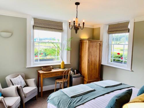 a bedroom with a bed and a desk and two windows at Hassop Station rooms on the Monsal Trail in Bakewell