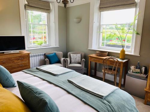 a bedroom with a bed and a desk and two windows at Hassop Station rooms on the Monsal Trail in Bakewell