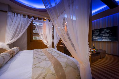 Schlafzimmer mit einem Bett mit weißen Vorhängen in der Unterkunft HOTEL Dior7 in Hamamatsu